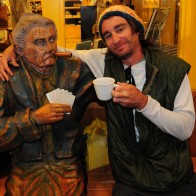 Randy Kalp sitting next to a wooden statue in Wall, South Dakota.