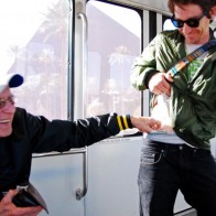 Old man is putting money down a hipsters pants on a Las Vegas monorail.