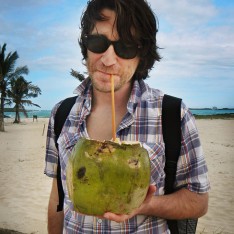A traveler holding out a coconut rum drink in the Galapagos Islands called the Coco Loco.