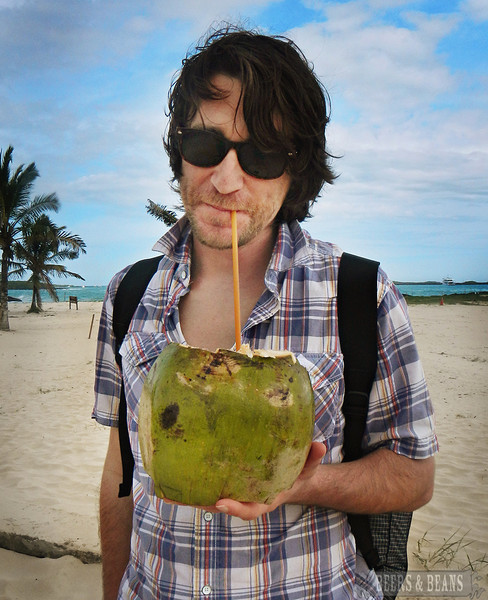 A traveler holding out a coconut rum drink in the Galapagos Islands called the Coco Loco.